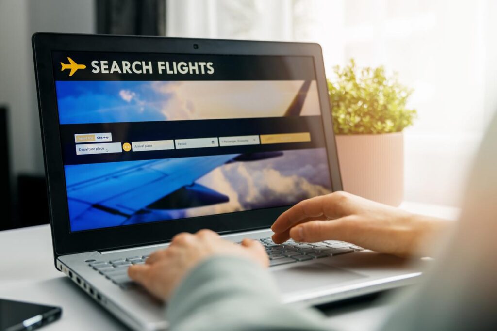 Person using a laptop to search for flights on an online booking website.