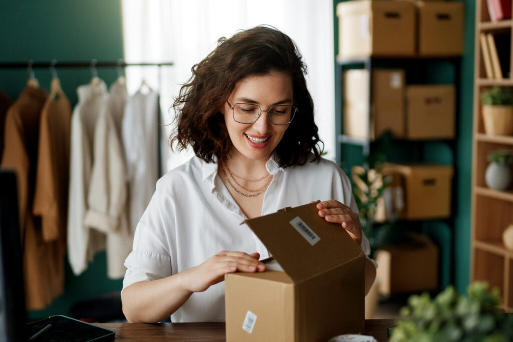 Small business owner packing an online order into a shipping box for customer delivery.